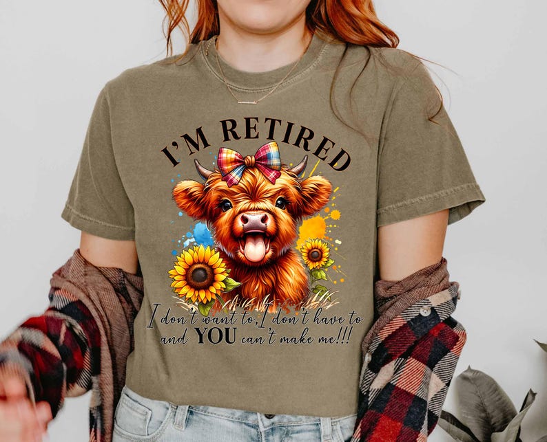 May include: Olive green t-shirt featuring a watercolor illustration of a Highland cow with a colorful bow, sunflowers, and the text "I'M RETIRED". The shirt also includes the text "I don't want to, I don't have to and YOU can't make me!!!".