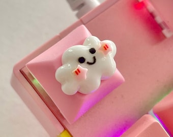 May include: A pink mechanical keyboard with a white cloud keycap featuring a smiling face and pink stars. The keyboard has a rainbow backlight.