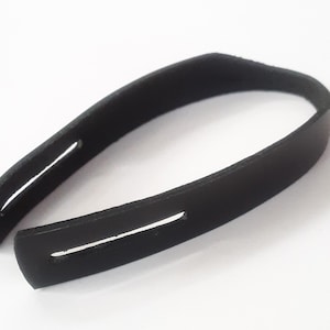 May include: Black leather strap with two stitched slots. The strap is curved and has a smooth finish.