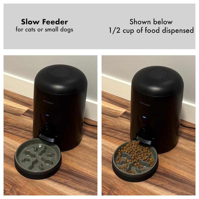 Op de afbeelding: Zwarte slowfeeder voor katten of kleine honden. De feeder geeft 1/2 kopje voer af in een grijze kom met een doolhofontwerp. De feeder is cilindrisch met een afgeronde bovenkant en een klein blauw lampje.