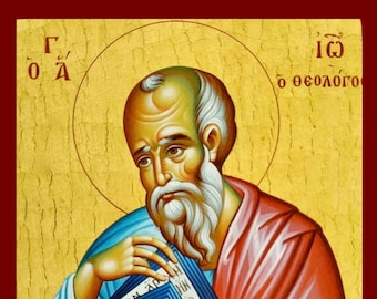 May include: An icon depicting a saintly figure with a white beard and halo, holding a book. The figure is dressed in red and blue robes against a gold background. The image has Greek text in the upper corners and around the halo.