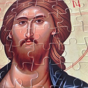 May include: A close-up of a jigsaw puzzle depicting a painting of Jesus Christ. The puzzle is mostly complete, with only a few pieces missing. The image shows Jesus's face, beard, and hair, with a golden halo behind him.