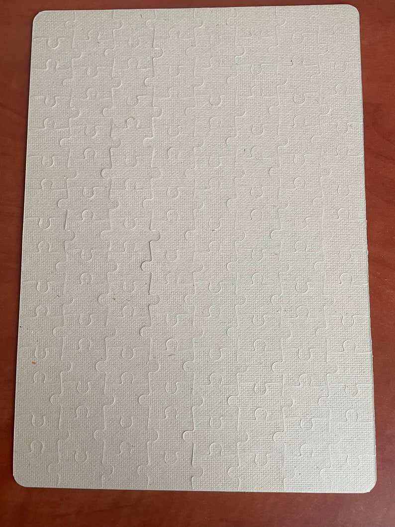 May include: A blank white jigsaw puzzle with a textured surface. The puzzle is made of cardboard and has a standard interlocking design.
