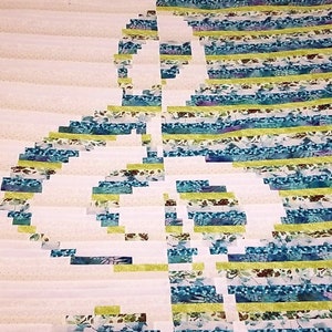 May include: A quilt with a white background and a design of a treble clef made from strips of fabric in shades of blue, green, and yellow.