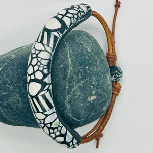 Pulseira expansível exclusiva, feita à mão. Confeccionada com trança de couro e argila polimérica.