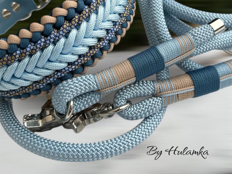 May include: Close-up of a dog collar and leash set in shades of blue and tan. The collar and leash are made of braided rope with metal hardware. The leash handle and collar feature decorative accents. The text "By Hulamka" is visible.