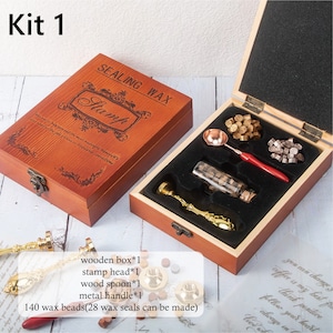 May include: A sealing wax kit in a wooden box labeled Kit 1. The set includes a metal stamp with a gold handle, a melting spoon with a red handle, a glass bottle of wax beads, and loose wax beads. Text on the box reads SEALING WAX Stamp.