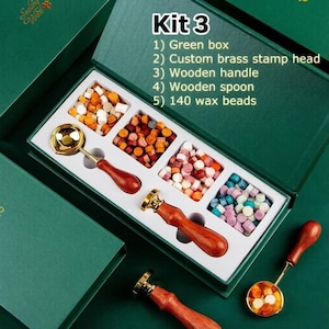 May include: A wax seal kit in a green box containing a custom brass stamp head, a wooden handle, a wooden spoon, and 140 wax beads. The kit includes four compartments of multicolored wax beads, a metal melting spoon, and two stamp handles.