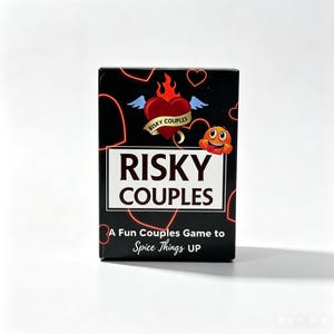 Puede incluir: Una caja de juego de cartas rectangular negra con el título RISKY COUPLES en letras blancas. El diseño presenta un corazón rojo con alas azules y llamas, una pequeña cara emoji naranja y contornos de corazones rojos de neón. El texto dice A Fun Couples Game to Spice Things UP.