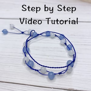 May include: A blue and white beaded bracelet with a navy blue cord. The bracelet is tied with a knot at the end. The image includes the text "Step by Step Video Tutorial".