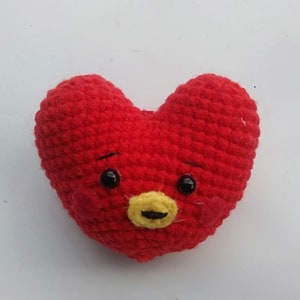 May include: Red crocheted heart-shaped plush toy with a yellow nose, black eyes, and a smiling expression.