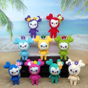 Puede incluir: Una colección de diez juguetes amigurumi de crochet en varios colores, incluyendo azul, verde, rosa, amarillo y morado. Cada juguete tiene una corona, flores y una expresión facial única. Los juguetes están dispuestos en semicírculo sobre una superficie de madera.