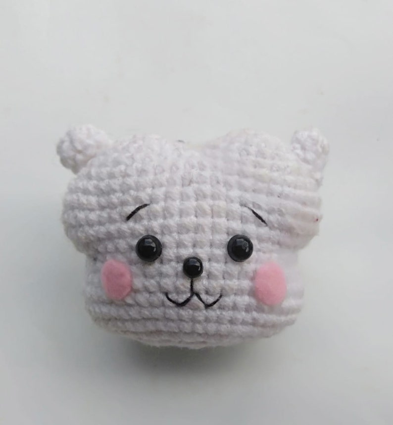May include: White crocheted stuffed animal with black eyes, a black nose, and pink cheeks.