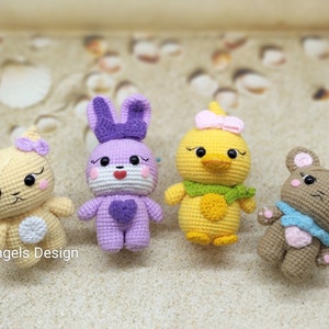 Puede incluir: Cuatro animales de peluche tejidos a crochet: un conejito morado con un corazón en el pecho, un pato amarillo con una bufanda verde, un oso marrón claro con una bufanda azul y un gato amarillo con un lazo morado.