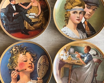 May include: Set of four decorative plates featuring illustrations by Norman Rockwell. Each plate depicts a different scene with a vintage aesthetic. The plates are white with gold trim and feature the artist's signature.