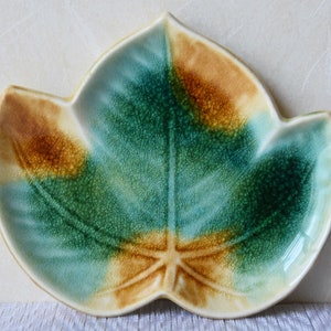 以下が含まれることがあります： 緑、青、茶色の釉薬をかけた、葉の形をした陶器の皿。スナックを盛り付けたり、小さなものを置いたりするのに最適です。