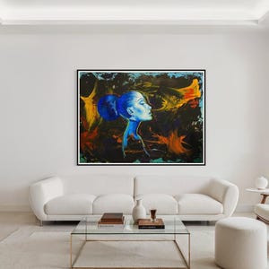 Pode incluir: Uma grande pintura quadrada em uma moldura preta retrata o perfil de uma mulher em tons de azul contra um fundo escuro e abstrato com pinceladas laranja e amarelas. A obra de arte est&aacute; pendurada acima de um sof&aacute; branco em uma sala de estar moderna.