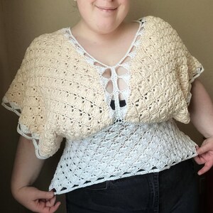 Op de afbeelding: Een gehaakt topje in wit en beige. De top heeft een V-hals en een losse pasvorm.