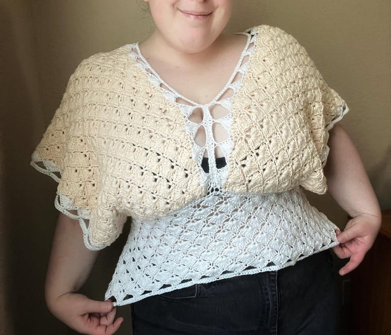 Op de afbeelding: Een gehaakt topje in wit en beige. De top heeft een V-hals en een losse pasvorm.