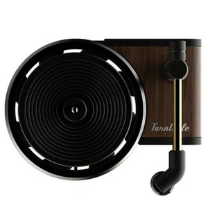 May include: A black and gold record player with a wooden base. The record player is mounted on a wall and has a circular turntable with a gold needle.