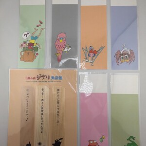 May include: A selection of illustrated bookmarks in various colours, including green, grey, orange, and pink. The bookmarks feature cartoon characters and Japanese text. The bookmarks are from the Ghibli Museum.