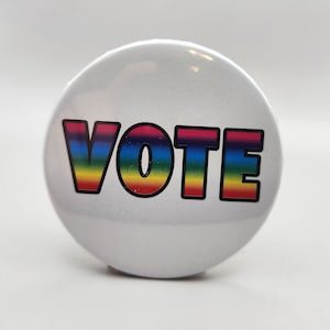 May include: A white button with the word "VOTE" in rainbow colors.