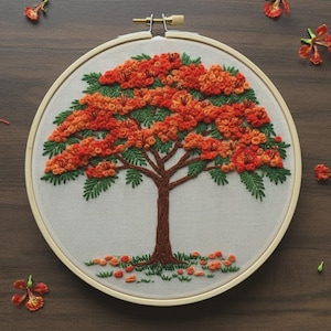 May include: Embroidered tree art in a wooden hoop. The tree features a brown trunk, green leaves, and vibrant orange flowers. The embroidery is set against a cream-colored fabric, with scattered orange flower details.