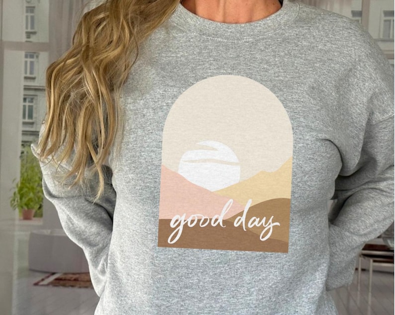May include: A gray sweatshirt with a graphic design of a sunset with the text "good day" in white.