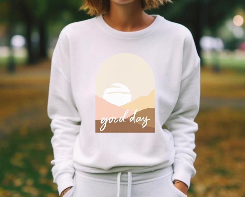 May include: White sweatshirt with a graphic design of a sunset with the text "good day" in brown and beige.