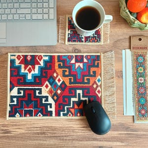 May include: A colorful patterned mousepad with fringe edges, a black computer mouse, and a bookmark with a colorful patterned design. The bookmark has the word "BOOKMARK" printed on it.