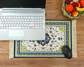 May include: A laptop computer sits on a blue and white patterned mouse pad with fringe. The mouse pad is on a wooden surface. A computer mouse is on the mouse pad.