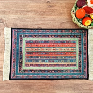 May include: A colorful rug with a geometric pattern and fringe edges. The rug is on a wooden surface.