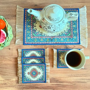 May include: Four blue and white patterned coasters with intricate designs. The coasters are made of fabric and have a fringed edge. A white teapot with a floral design sits on a matching coaster.