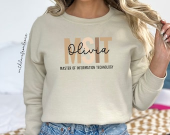 Peut inclure: Un sweat-shirt beige avec le texte "MSIT Olivia" et "MASTER OF INFORMATION TECHNOLOGY" imprimé sur le devant.