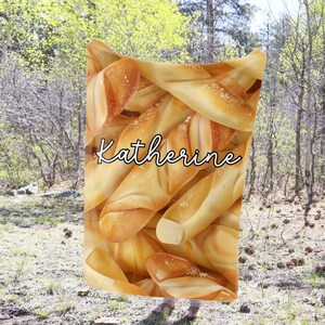 May include: A personalized blanket with a pattern of golden brown breadsticks. The name "Katherine" is written in white cursive on the blanket.