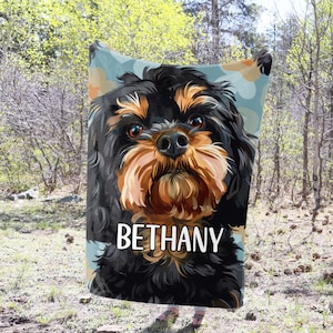 May include: A personalized fleece blanket with a colorful illustration of a black and brown dog. The dog's name, "Bethany", is printed in white text on the blanket.