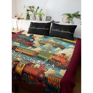 May include: A red, blue, and green train themed duvet cover with a personalized name "Alexander" in white cursive script. The duvet cover features a vintage illustration of trains traveling through the clouds. The pillowcases are black with white cursive text that reads "with love from Leona".