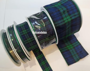 May include: Several rolls of plaid ribbon in shades of navy blue and green. The ribbon is wrapped around white spools and encased in clear plastic. A length of ribbon extends from one of the rolls.