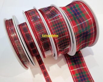 May include: Several spools of red plaid ribbon with green and blue accents. The ribbon is on white spools and is partially unrolled, revealing the pattern. The image is well-lit, showcasing the texture and colors of the ribbon.