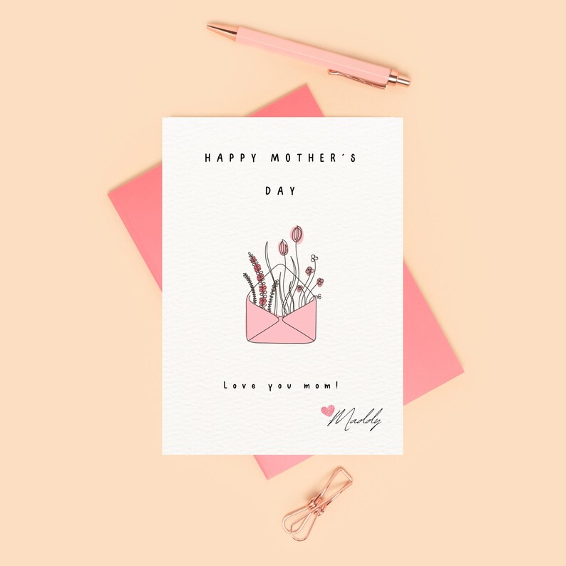 May include: A pink card with the text "Happy Mother's Day" and a pink envelope with flowers inside. The card also says "Love you mom!" and is signed "Maddie".