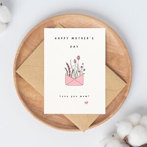 May include: A white card with a pink envelope filled with flowers and the text "Happy Mother's Day" and "Love you mom!"