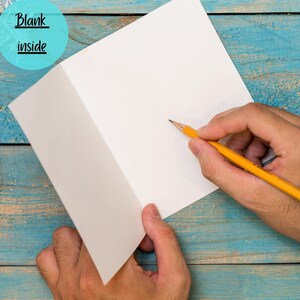 May include: A blank white card with a yellow pencil on a blue wooden background. The card is open and ready to be written on. The text "Blank inside" is written on a blue circle in the top left corner of the image.