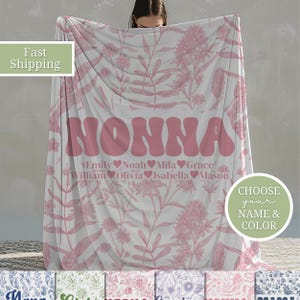 May include: A pink floral patterned fleece blanket with the word "NONNA" in a pink retro font. The blanket also has a list of names and hearts below the word "NONNA".