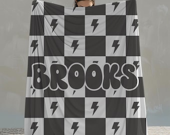May include: Black and white checkered fleece blanket with the word "BROOKS" in large, white, bubble letters. The blanket has a lightning bolt pattern on each square.