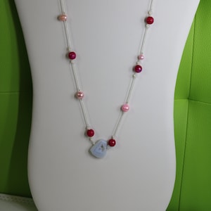 Könnte beinhalten: Eine lange silberne Kettenkette mit rosa und roten Perlen und einem Anhänger aus blauem Achat.