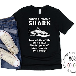 May include: Black t-shirt with a white graphic of a shark and the text "Advice from a SHARK Take a bite of life Stay active Fin for yourself Live fiercely Stay sharp!"