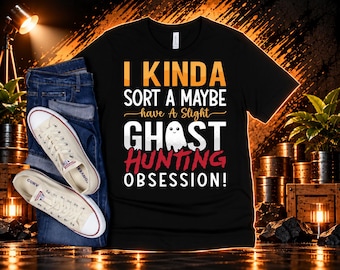 May include: A black short-sleeved t-shirt featuring the text I KINDA SORT A MAYBE have A Slight GHOST HUNTING OBSESSION! with a small white ghost illustration, paired with blue denim jeans and white canvas sneakers.