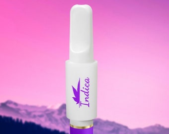May include: White vape pen with a purple and gold mouthpiece. The pen has a purple leaf design and the word "Indica" printed on the side.