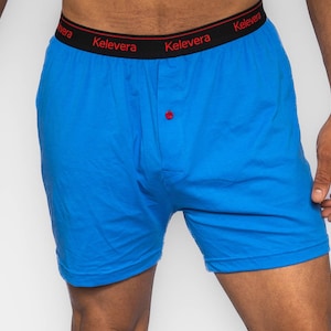 Puede incluir: Bóxers azules con cintura negra y bragueta con botón rojo. La cintura tiene la palabra "Kelevera" impresa en blanco.