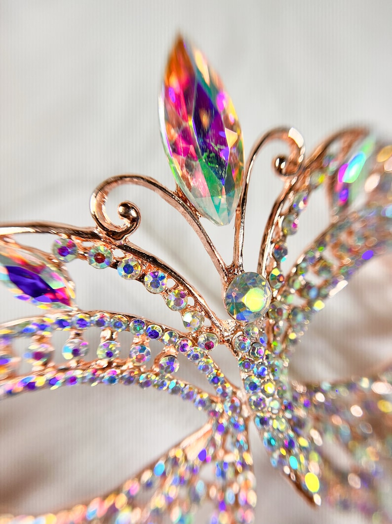 Pu&ograve; includere: Un fermaglio per capelli a forma di farfalla in oro rosa con strass iridescenti. La farfalla ha un design delicato ed &egrave; adornata con cristalli scintillanti.